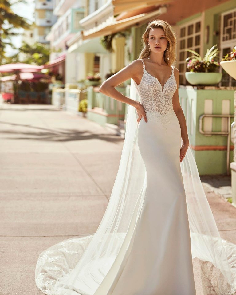 Elegant mermaid wedding dress, made in crepe with beadwork. This haute-couture Luna Novias gown features a V-neckline, open back, straps, and an enchanting tulle with  lace beadwork cape. LUNA_NOVIAS.