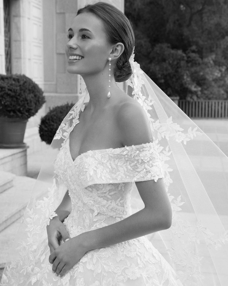Vestido de novia de corte princesa y estilo romántico, elaborado con encaje y pedrería. Con escote bajo hombros, espalda abotonada y manga caída, este modelo de ensueño Luna Studio te enamorará. LUNA_NOVIAS.