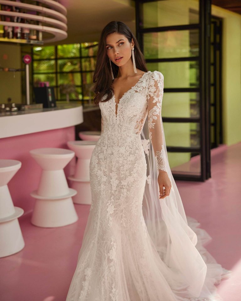 Vestido de novia largo de dos piezas con corte sirena. Encaje y pedrería, escote pico, mangas extraíbles, espalda ilusión y capa. LUNA_NOVIAS.