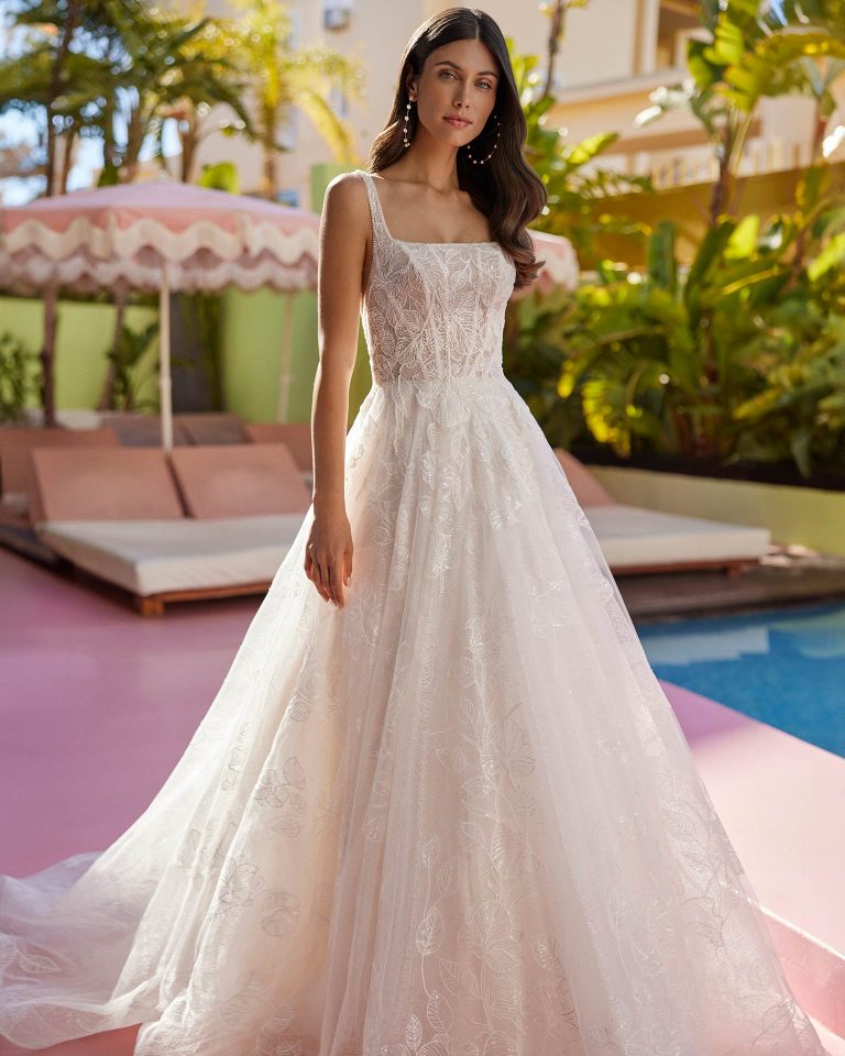 Vestido de novia largo de corte princesa. Encaje y pedrería, escote cuadrado, tirantes y espalda con tira de pedrería. LUNA_NOVIAS.