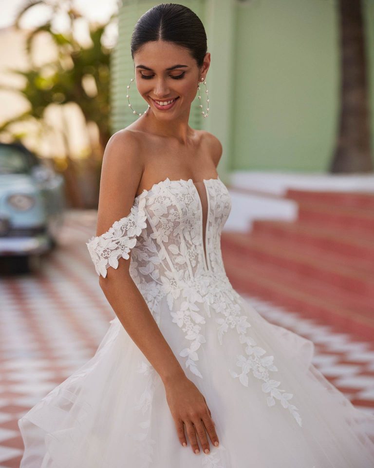 Vestido de novia largo de corte volumen. Encaje y pedrería, escote profundo, tirantes caídos y espalda escotada. LUNA_NOVIAS.