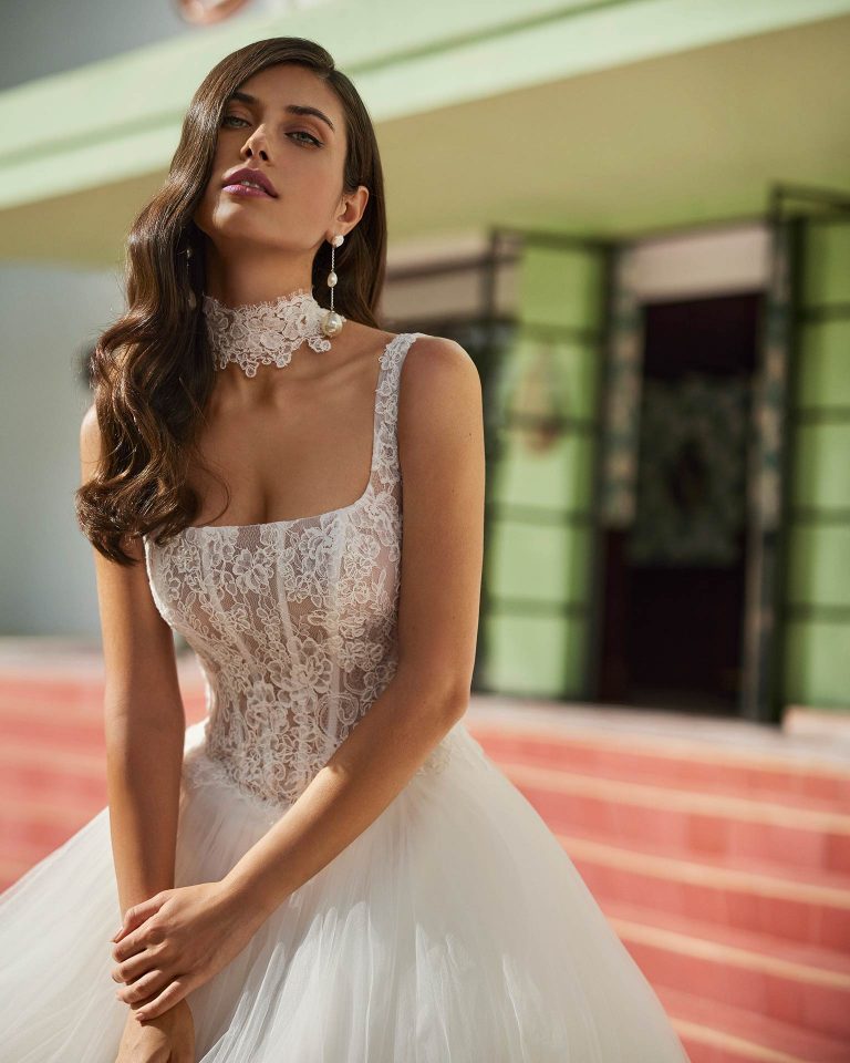 Vestido de novia largo de corte volumen. Encaje y pedrería, escote cuadrado, tirantes y espalda con corsé y choker. LUNA_NOVIAS.