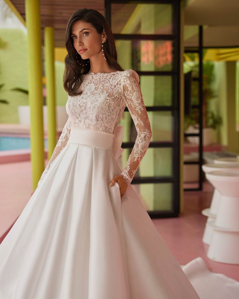 Vestido de novia largo de corte volumen. Mikado, escote barco, manga larga, espalda en V y lazo. LUNA_NOVIAS.