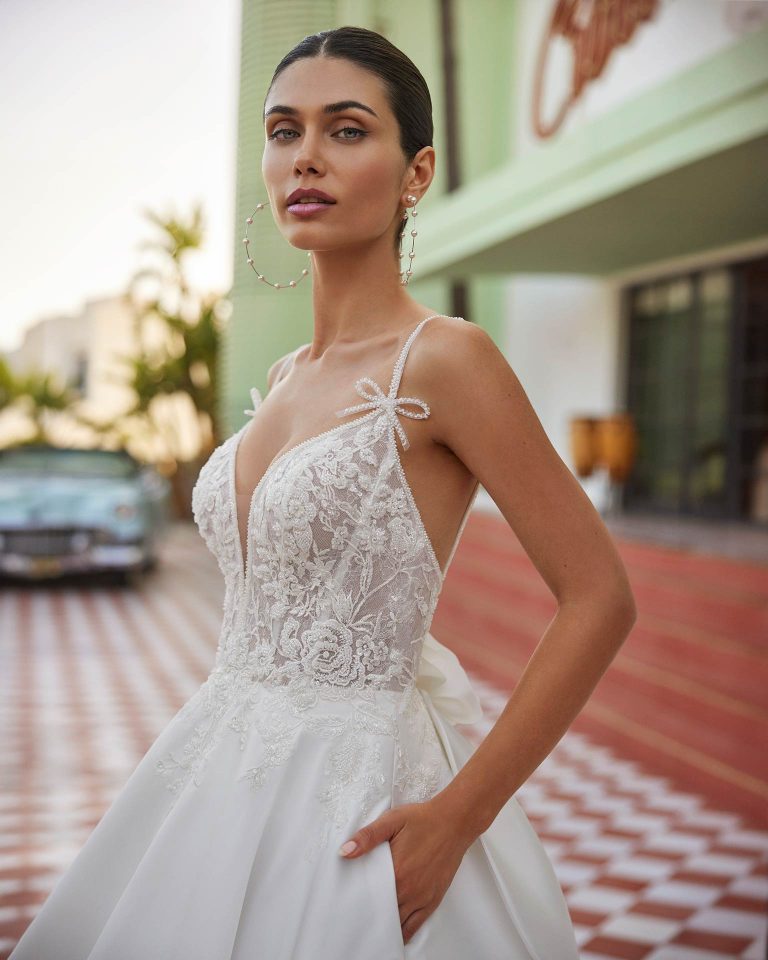 Vestido de novia largo de corte volumen. Mikado, escote pico, tirantes de pedrería, espalda escotada y lazo. LUNA_NOVIAS.