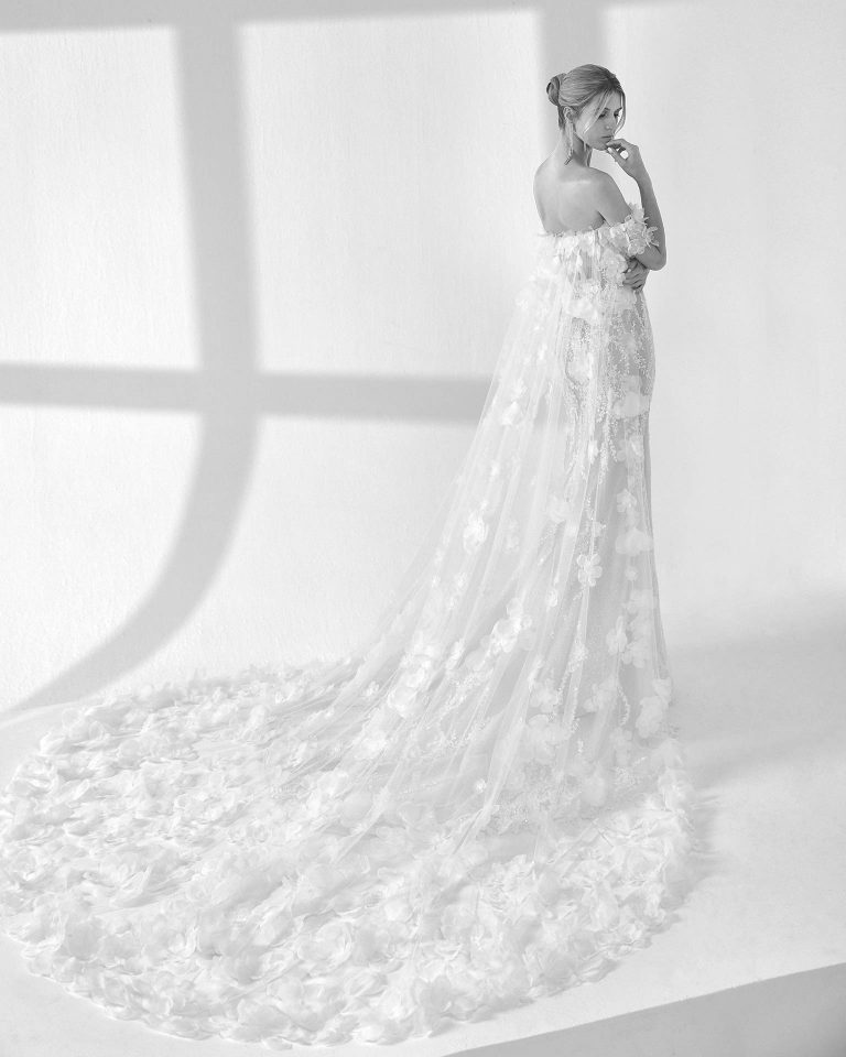 Vestido de novia largo de dos piezas con corte sirena. Pedrería, escote corazón, tirantes caídos y espalda descubierta con capa. LUNA_NOVIAS.