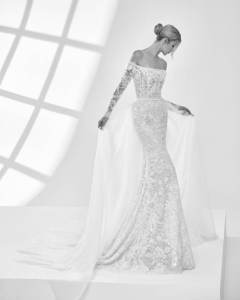 Vestido de novia largo de dos piezas con corte sirena. Pedrería, escote palabra de honor, manga larga y espalda cerrada con sobrefalda. LUNA_NOVIAS.