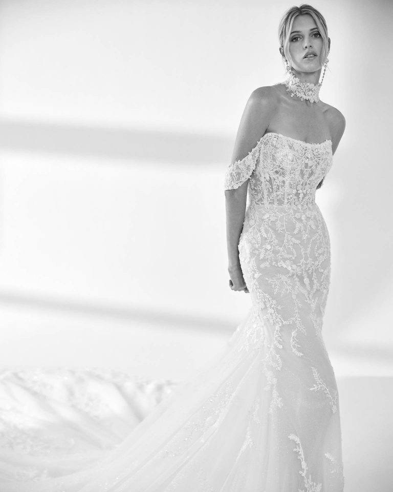 Vestido de novia largo de corte sirena. Encaje y pedrería, escote palabra de honor, tirantes caídos y espalda descubierta con choker. LUNA_NOVIAS.