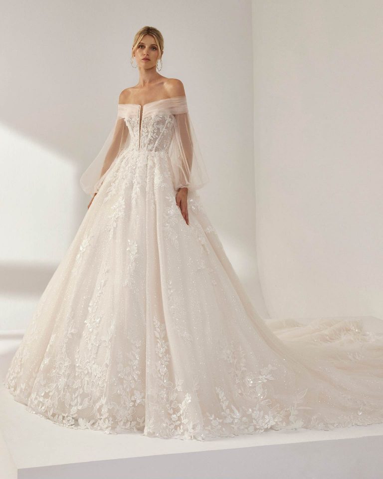 Vestido de novia largo de corte volumen. Tul nevado, escote palabra de honor, mangas extraíbles y espalda con corsé y cuello envolvente extraíble. LUNA_NOVIAS.