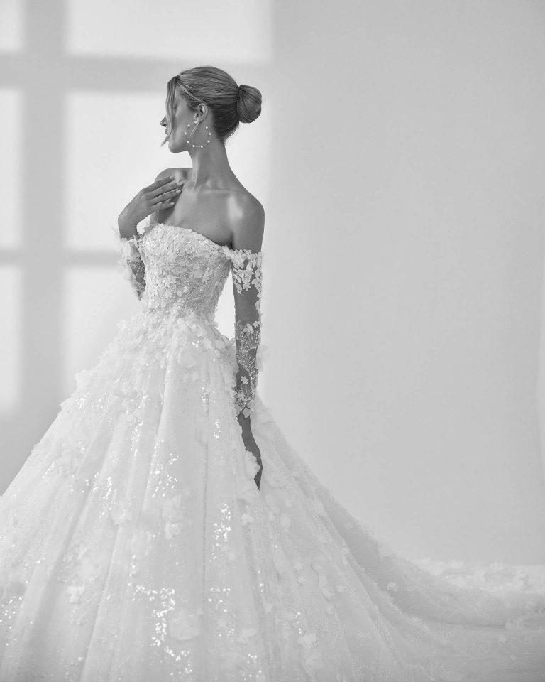 Vestido de novia largo de corte volumen. Tul glitter nevado, escote palabra de honor, manga larga y espalda descubierta. LUNA_NOVIAS.