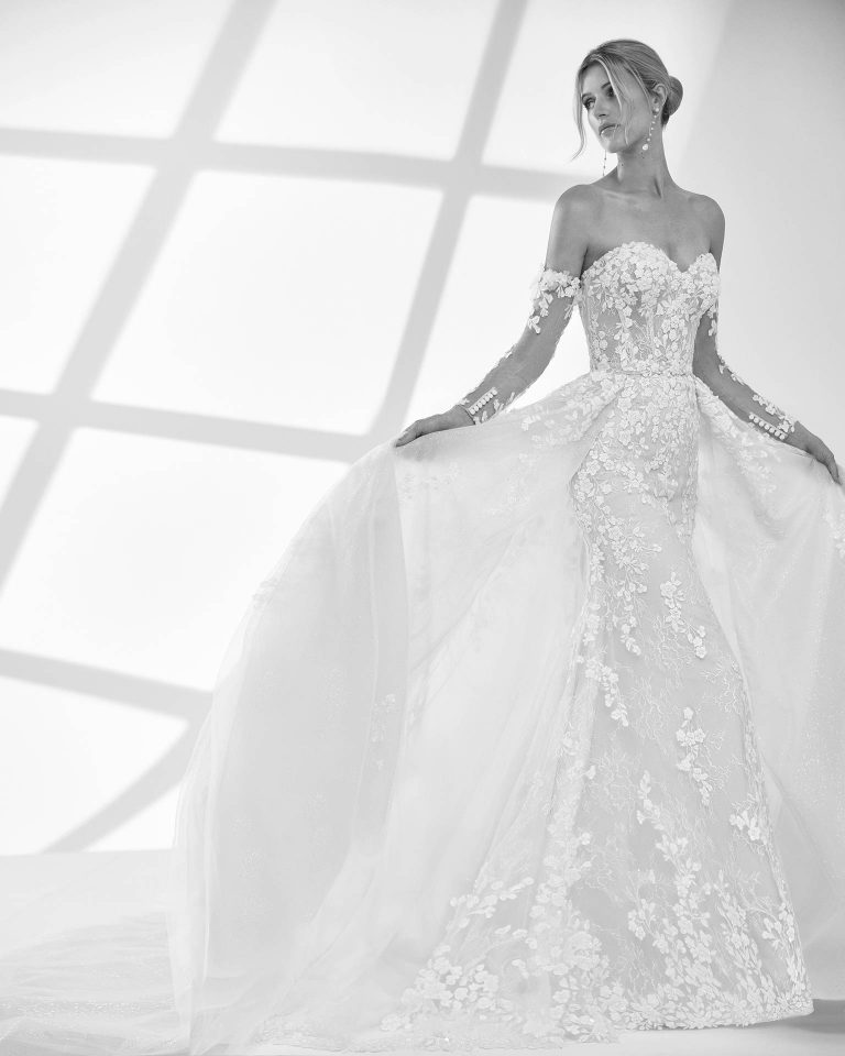 Vestido de novia largo de dos piezas con corte sirena. Encaje y pedrería, escote corazón, mangas extraíbles y espalda descubierta con sobrefalda y choker. LUNA_NOVIAS.