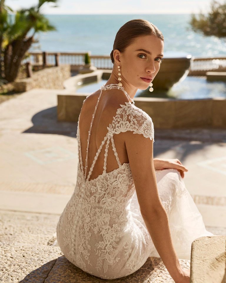 Mermaid silhouette wedding dress with deep neckline and open back. Short sleeve with lace. Lace bodice with beadwork and appliqués. Lace skirt. LUNA_NOVIAS.