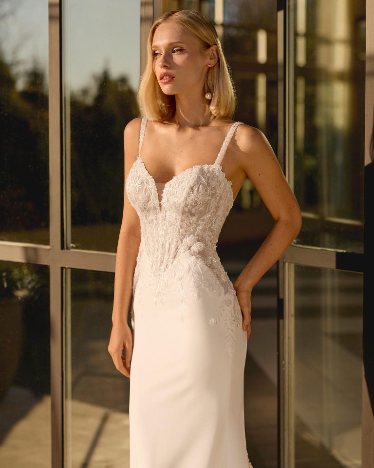 Mermaid wedding dress with plunging neckline and straps. Open back. Lace bodice and bi-elastic crepe skirt with lace and appliqués. LUNA_NOVIAS.