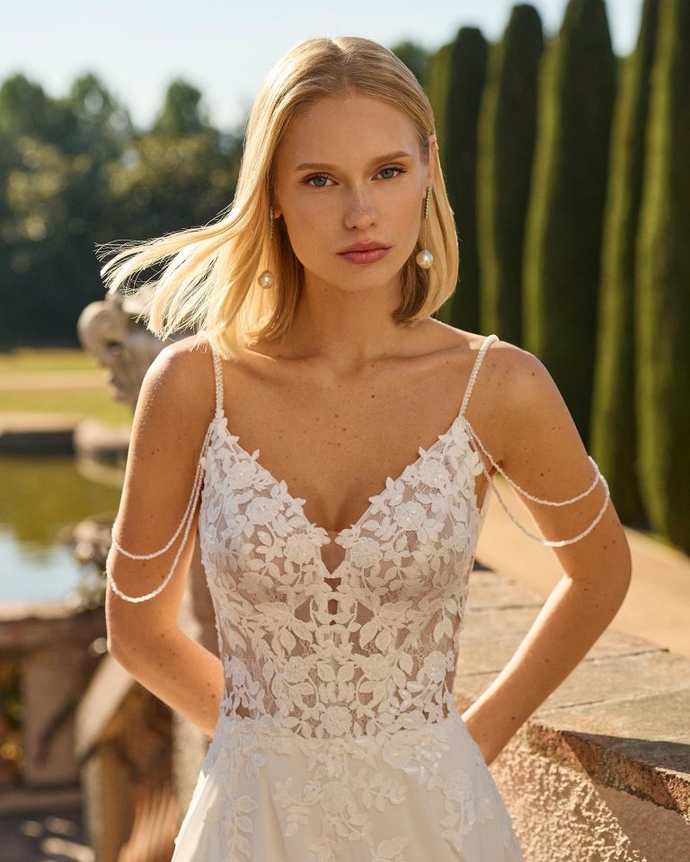 Straight wedding dress with deep neckline, embellished straps, lace bodice, georgette skirt with lace details and open back. LUNA_NOVIAS.
