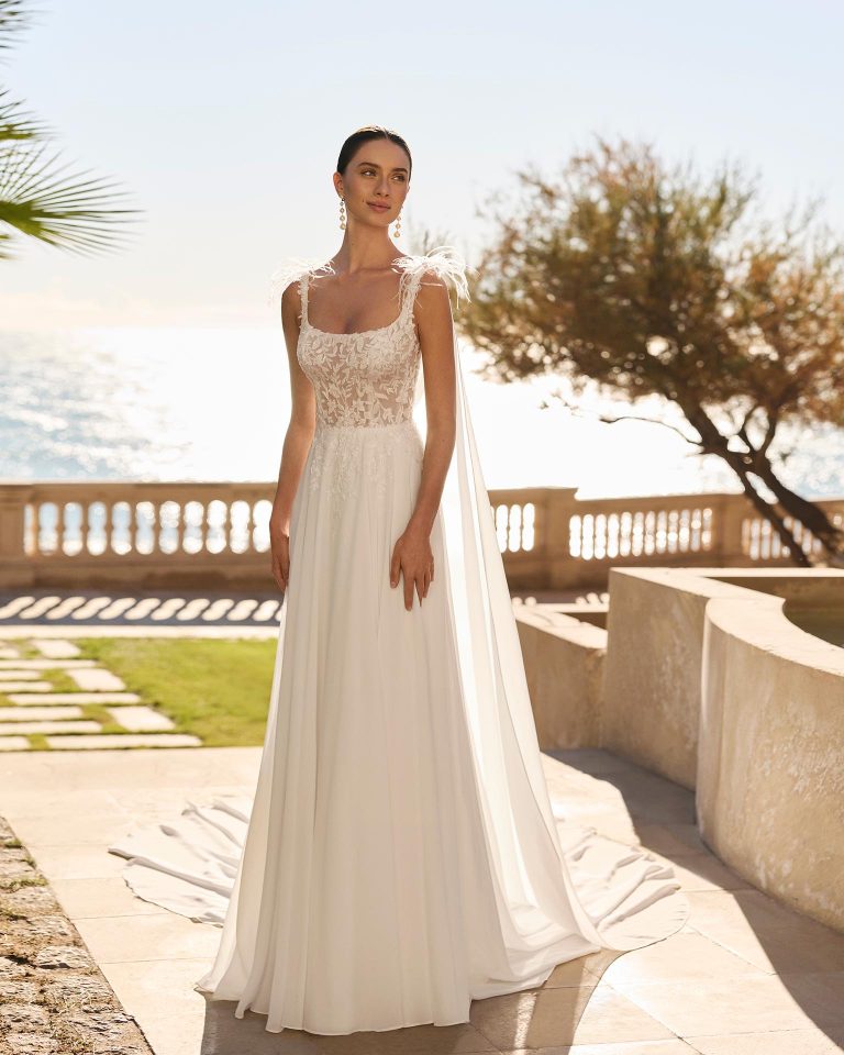 Two-piece wedding dress with straight silhouette. Lace bodice with feathered straps and square neckline. Open back. Georgette skirt. Includes georgette cape. LUNA_NOVIAS.