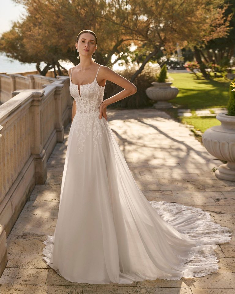 Straight silhouette wedding dress with deep neckline, open back and straps. Lace bodice and georgette skirt with lace embellishments. LUNA_NOVIAS.