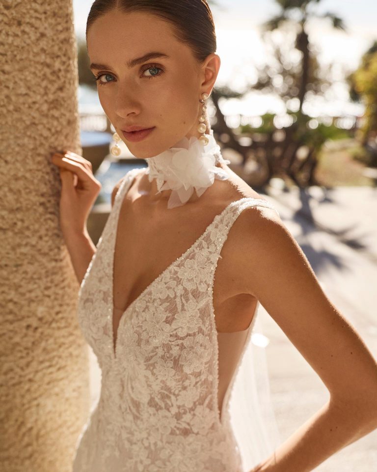 Two-piece mermaid silhouette wedding dress. Made of lace with beadwork. Deep neckline with straps and V-back. Includes choker with tulle cascades featuring lace and beadwork. LUNA_NOVIAS.