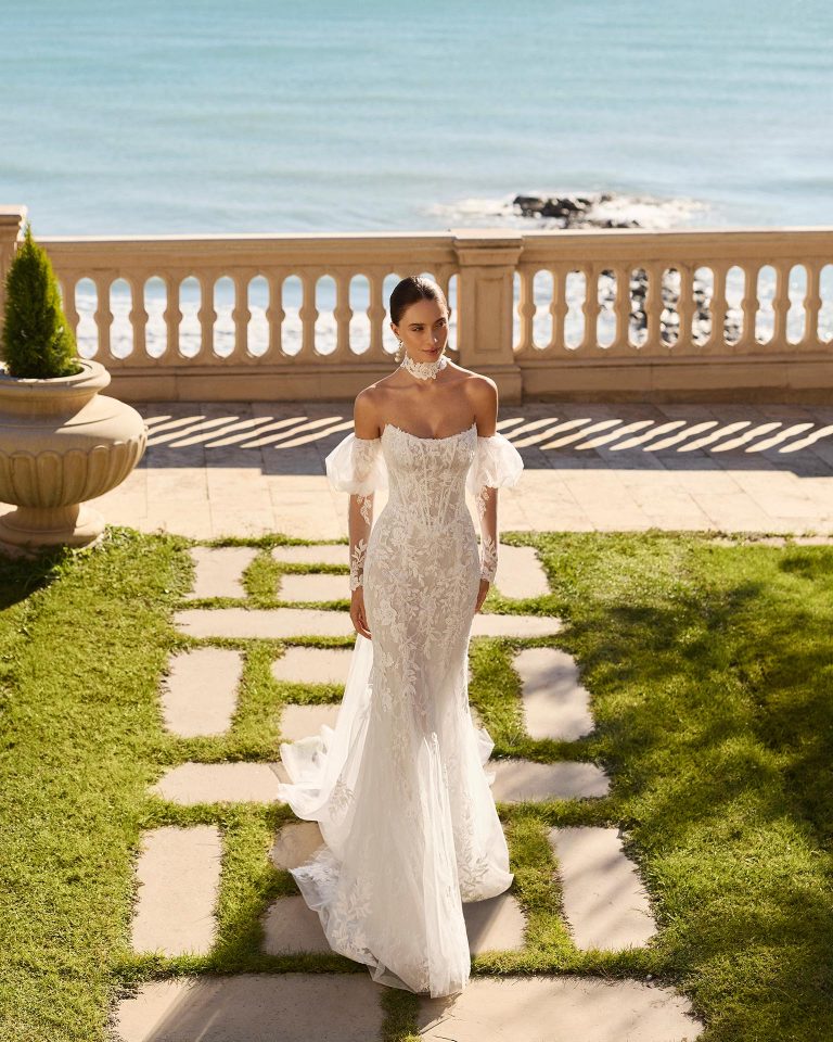 Two-piece mermaid silhouette wedding dress in lace. Sweetheart neckline, long off-shoulder sleeves with beading on the bodice and choker with draping details. LUNA_NOVIAS.