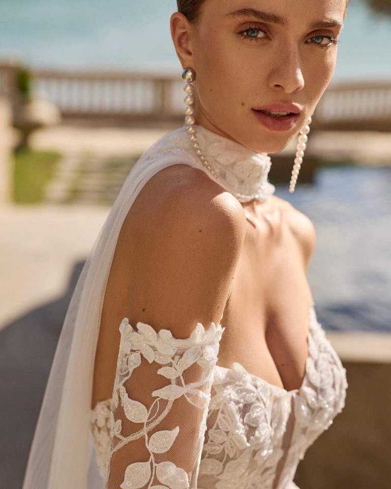 Two-piece mermaid silhouette wedding dress. Deep neckline and long off-shoulder sleeve in lace with beading. Includes plain tulle shawl. LUNA_NOVIAS.