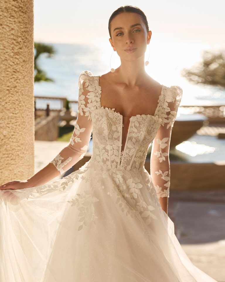 A-line wedding dress with sweetheart neckline. Beaded lace bodice with removable long lace sleeves. Plain tulle skirt with appliqués. LUNA_NOVIAS.