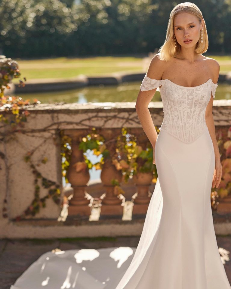 Two-piece mermaid silhouette wedding dress with strapless neckline, removable off-shoulder straps, lace bodice with beadwork, elastic mikado skirt, corset closure and choker. LUNA_NOVIAS.