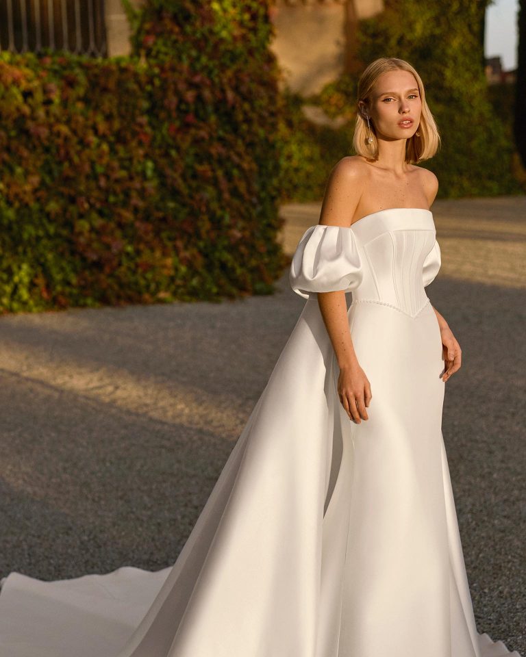 Two-piece bridal gown, mermaid silhouette in elastic mikado. Strapless neckline, puff sleeve, corset with beadwork. Includes cape. LUNA_NOVIAS.