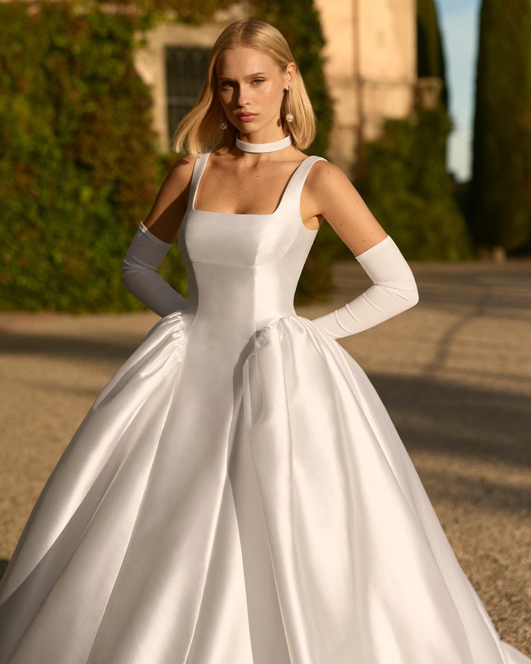 Princess silhouette wedding dress with square neckline, straps and square back. Made in mikado shantung with plain skirt. Choker included. LUNA_NOVIAS.