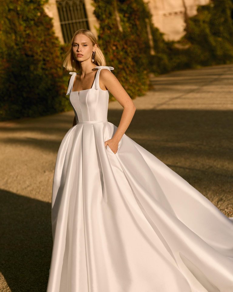 Princess silhouette wedding dress in mikado with square neckline, square back, bow strap details. Plain bodice and skirt. LUNA_NOVIAS.