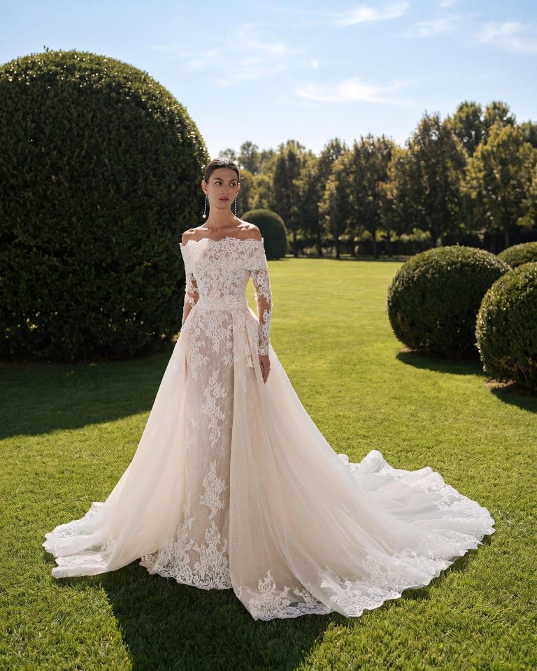 Three-piece bridal gown with mermaid silhouette, sweetheart neckline, made of lace with detachable long sleeves. Includes overskirt and tulle collar. LUNA_NOVIAS.