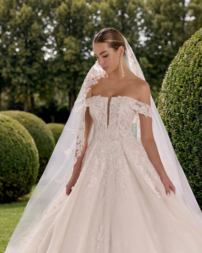 Princess silhouette wedding dress with off-shoulder neckline. Beaded lace bodice and removable long lace sleeves. LUNA_NOVIAS.