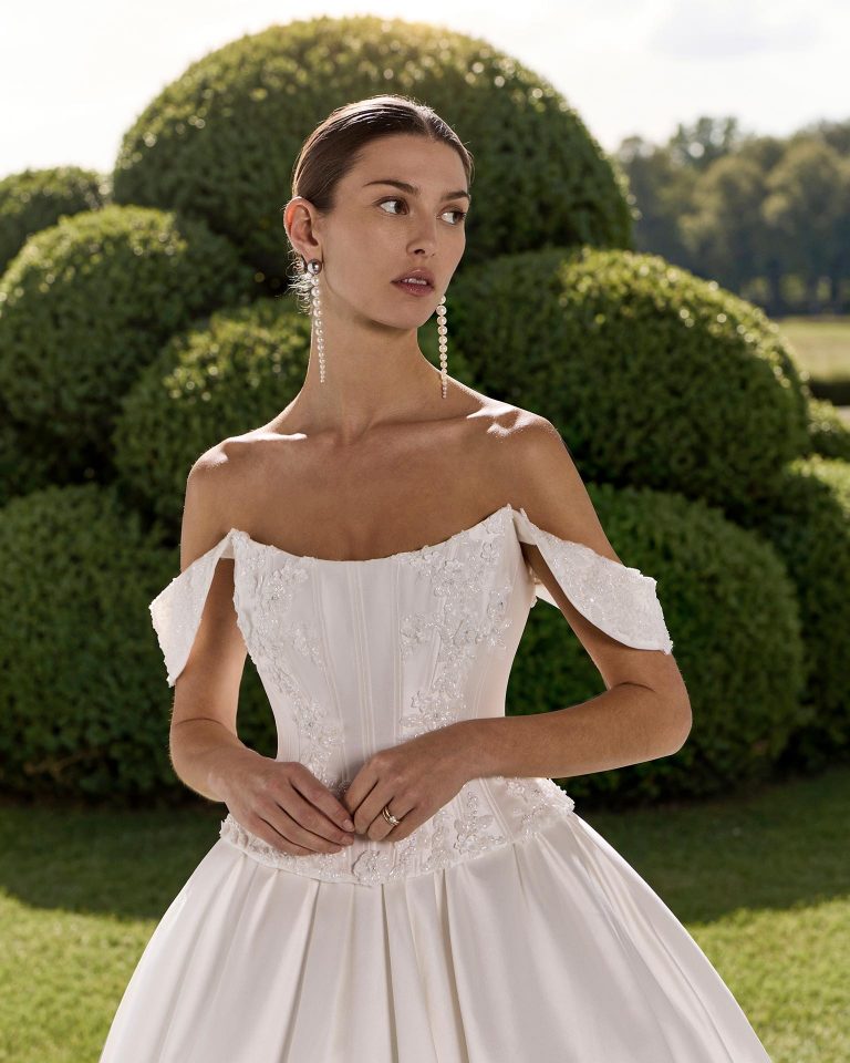 Two-piece wedding dress, princess silhouette in mikado. Sweetheart neckline with off-shoulder straps, beading and corset-style back closure. LUNA_NOVIAS.